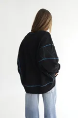 Buzo negro de felpa de algodón con pespuntes en zigzag color celeste y logo bordado en el pecho.