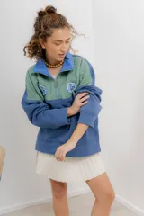 Buzo de algodón con cierre metálico y bordados de flores. Diseño color block en verde y azul.
