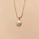 Conjunto de collar y aros de oro amarillo 18k con dije de trébol con incrustaciones de nácar. Incluye cadena de eslabones finos y aros colgantes con cierre de gancho.