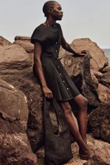 Vestido corto negro de algodón con escote redondo, manga japonesa, botonadura frontal y cintura entallada con pinzas. Falda acampanada con inserciones para dar volumen.