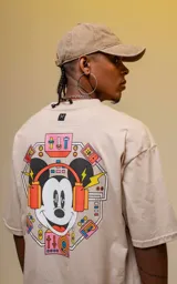 Remera color beige de manga corta con cuello redondo y calce oversize. Estampado en la espalda con diseño de Mickey Mouse con auriculares y elementos de audio.