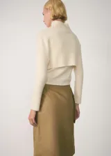 Sweater corto color crema de punto canalé con cuello alto.