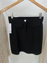 Minifalda negra de bengalina elastizada con bolsillos falsos, cierre y botón metálico.