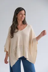 Poncho de tejido de punto color crudo, con escote en V y detalle calado en el ruedo.