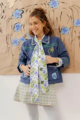 Chaqueta de pana terciopelo azul con bordados a mano y a máquina, con cuello clásico, cierre frontal con botones y bolsillos delanteros.