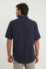 Camisa sport de manga corta color verde oliva, línea premium, con cuello clásico, cierre frontal con botones de coco y bolsillo de parche en el pecho. Confeccionada en lino y algodón.