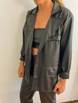 Blazer negro de cuerina, con corte clásico y bolsillos frontales.