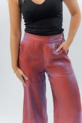 Pantalón de lino con acabado metalizado tornasolado, que refleja tonos entre rosa y lila según la luz. De corte recto y largo ¾, tiene cintura con elástico en la espalda que aporta comodidad y un calce relajado.