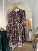 Vestido corto con estampado animal print, de mangas largas traslúcidas y falda con volados.