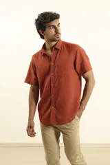 Camisa sport de manga corta color verde oliva, línea premium, con cuello clásico, cierre frontal con botones de coco y bolsillo de parche en el pecho. Confeccionada en lino y algodón.