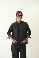 Camisa negra de manga larga y corte semi holgado, con canesú en la espalda, abotonada en el frente y con cuello camisero.
