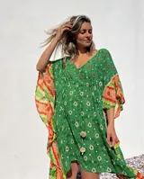 Túnica corta verde con estampado de flores blancas y detalles bordados en el escote. Mangas anchas con terminación en tela estampada a rayas naranjas y blancas.