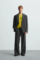 Blazer negro de corte relajado con cuello de solapa de muesca desmontable, manga larga, bolsillos frontales ocultos y cierre frontal con botones.