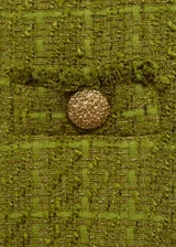 Chaqueta corta de tweed color verde oliva, con cuello redondo, cuatro bolsillos frontales y botones decorativos.