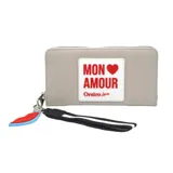 Billetera gris con cierre perimetral, tira de agarre con cinta de rayas horizontales blancas y negras, y charm colgante con forma de labios. Estampa frontal con la frase "Mon Amour" y logo de la marca.
