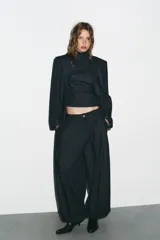 Pantalón bombacho de denim azul oscuro, tiro medio, con bolsillos laterales ocultos y de parche en la espalda. Presenta pinzas en la parte delantera y bajo abullonado con elástico.
