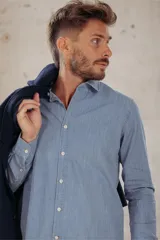 Camisa celeste de corte clásico, manga larga y cuello abotonado.