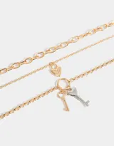Set de tres collares dorados de diferentes largos, con eslabones de distintos tamaños. Incluye un dije de corazón y un dije de llave.
