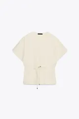 Camiseta color crudo de algodón con cuello redondo, manga corta caída y cintura ajustable con cordón.