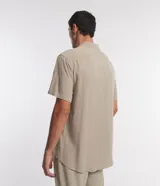Camisa boxy masculina de viscosa color beige, con mangas cortas, cuello camisero y abotonadura frontal.