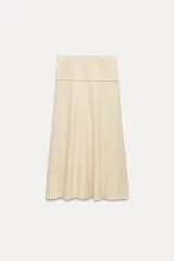 Falda midi color crema, de tiro alto con cintura elástica y corte evasé.