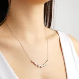 Collar plateado con cadena fina y dije curvo con incrustaciones de circonitas blancas.