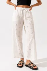 Pantalón de algodón blanco con bordado tipo broderie de flores, de corte holgado y tiro alto.