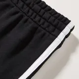 Pantalón jogger Adidas negro con las icónicas tres rayas blancas a lo largo de las piernas. Presenta un corte cónico (tapered) con puños acanalados y el logo de Adidas bordado en blanco en el muslo izquierdo.