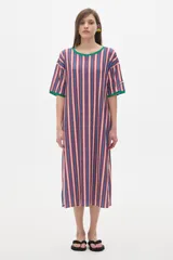 Vestido midi de corte recto con rayas verticales rojas, azules y blancas, cuello redondo y mangas cortas con ribete verde.