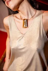 Collar dorado tipo cuellera con dije rectangular grande.