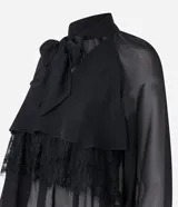 Blusa negra de chiffon con cuello alto con lazo, mangas largas con puños ajustados, detalle de volado delantero y volado en encaje.