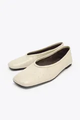 Zapato tipo bailarina color crema con relieve en el cuerpo, detalle de pespunte en el cerco y acabado en punta redonda.