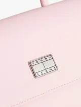 Cartera Tommy Jeans color rosa con asa superior, correa ajustable negra, cierre de solapa magnético, dos compartimentos principales y bolsillo interior con cremallera.