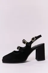 Zapato de tacón negro de cuero, con punta redondeada, plataforma y dos tiras sobre el empeine con hebillas doradas.