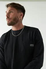 Remera color marrón de manga larga, con bolsillo en el pecho y logo de la marca en etiqueta sobre el bolsillo.