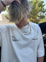 Remera amarilla con estampado en la espalda de una camioneta con una chica y una tabla de surf.