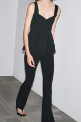 Top blanco de tejido elástico, con escote redondo, tirantes anchos y bajo peplum.