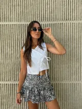 Blusa blanca cruzada de lino y algodón, sin mangas, con lazos laterales para ajustar.