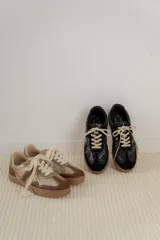 Championes acordonados color beige y dorado con suela marrón.