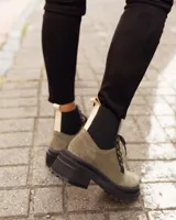 Borcego de gamuza color verde militar con elásticos laterales negros, cordones negros y suela de goma negra con plataforma.