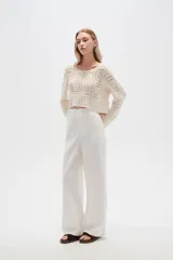 Pantalón blanco de lino, de corte recto y tiro alto, con bolsillos laterales.