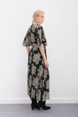 Vestido largo negro con estampado floral dorado en lurex, escote en V cruzado, mangas al codo, cintura elastizada con lazo y viso al tono con breteles regulables y puntilla en el escote.