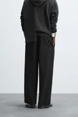 Pantalón negro de corte ancho, con pinzas en la cintura, bolsillos laterales y traseros de ojal.