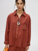 Camisa celeste de corte holgado con bolsillo en el pecho con logo bordado. Detalle de diseño en cartera de botones y puños con ribete a contraste.