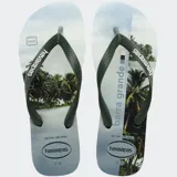 Ojotas Havaianas con base blanca estampada con paisaje tropical y tiras verdes con textura.