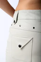 Minifalda de cuero color crema con cierre frontal con cremallera y bolsillos tipo cargo con botón a presión.