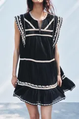 Minivestido negro de algodón con bordados florales blancos en cuello, mangas y ruedo.
