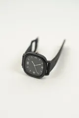 Reloj de pulsera negro con caja cuadrada y correa de silicona con hebilla.