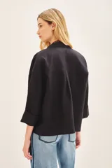 Saco corto de lino negro, de corte oversize con mangas amplias y cruce frontal con doble abotonadura.