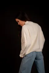 Sweater color crudo con cuello alto y diseño trenzado.